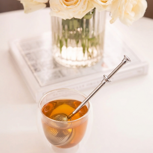 LittleCalm tea infuser brewing loose leaf herbal tea in a double-walled glass cup.