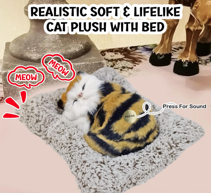 Cat plush toy with a bed, realistic and lifelike, on a soft surface.