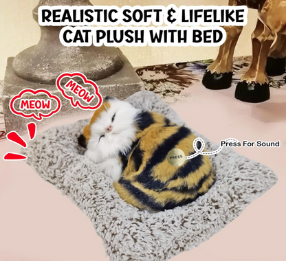 Cat plush toy with a bed, realistic and lifelike, on a soft surface.