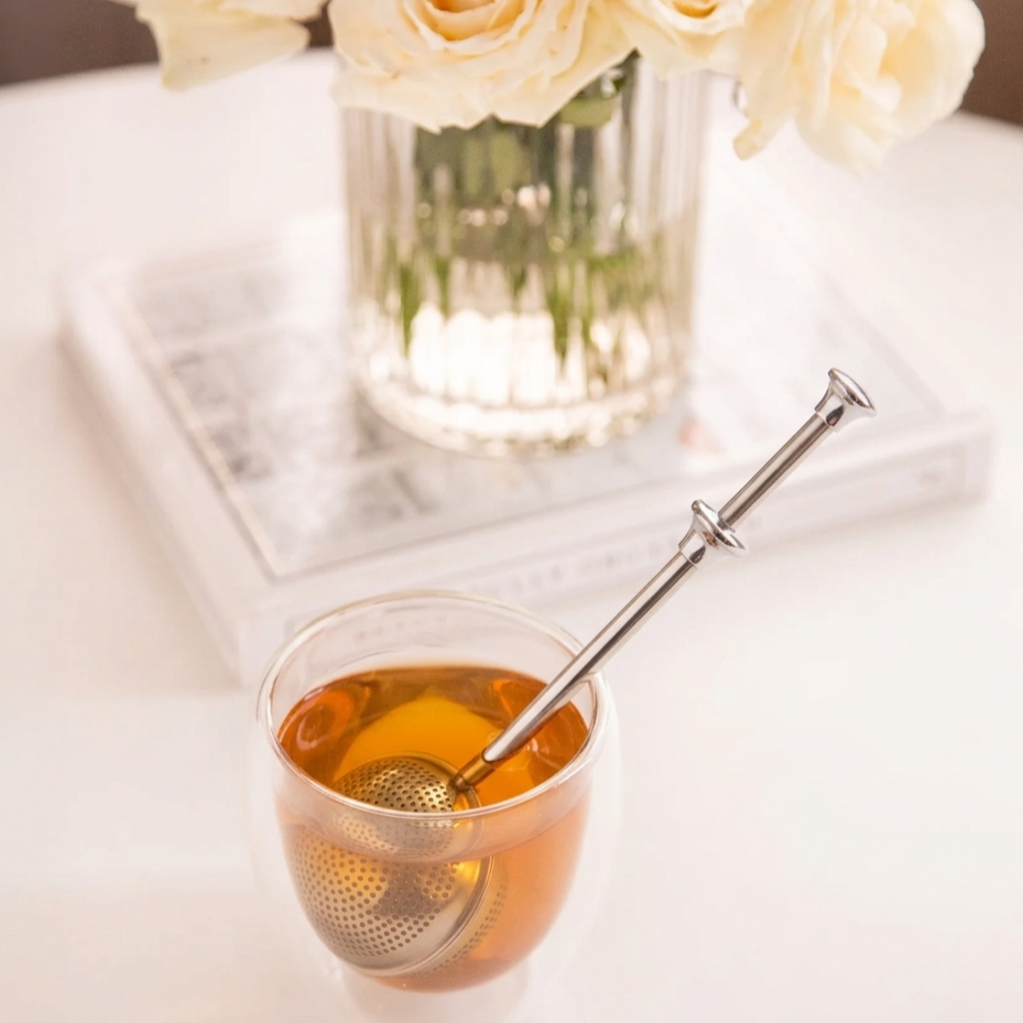 LittleCalm tea infuser brewing loose leaf herbal tea in a double-walled glass cup.